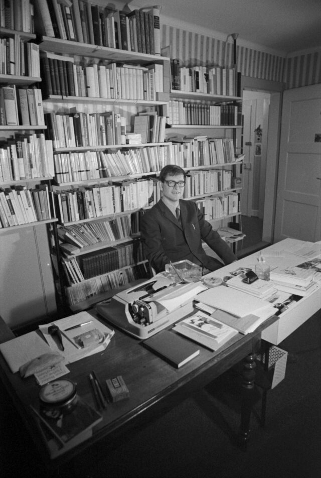 Der 28-jährige Schriftsteller Hermann Burger am Pult vor einer Bücherwand sitzend