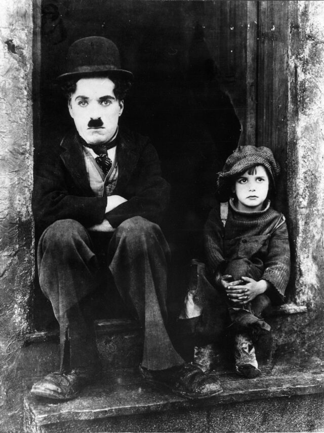 Charlie Chaplin in Filmrolle Der Vagabund" auf Treppenabsatz mit Kind "