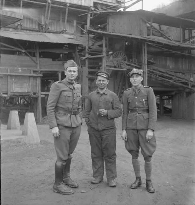 Mann in Zivil und zwei Schweizer Armeeangehörige vor Minen (Mines de Chandolin, Sion ?) (Aufnahme für Fernand Dussex, Café Salins)