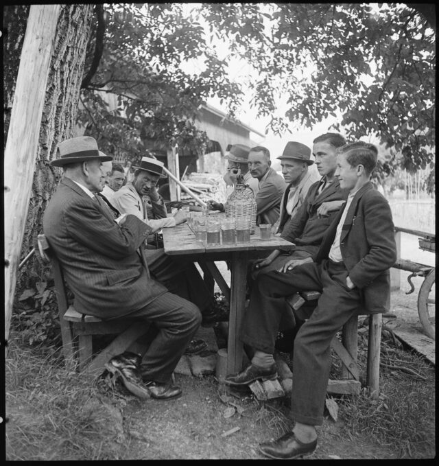R454: Männer sitzen an einem Tisch im Freien