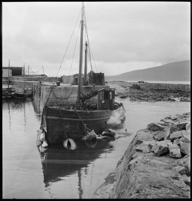 40: 40: Schiff vertäut im Hafenbecken, im Hintergrund drei Personen auf der Mole