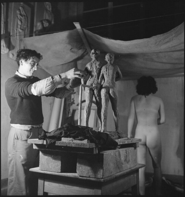 R729: Franco Annoni arbeitet an Skulptur, Modell in Pose mit Rücken zu Annoni