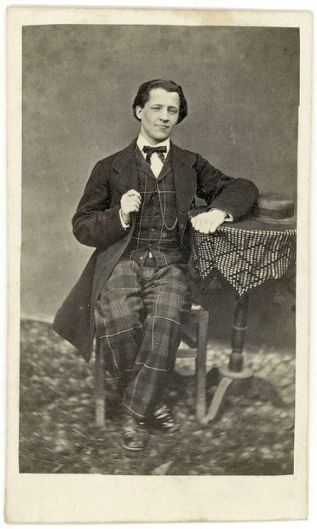 Giovane uomo con abito scozzese e cappello