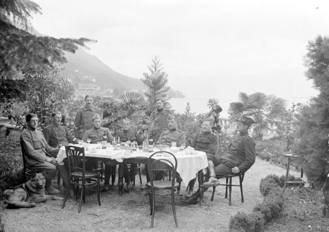 Offiziere am Mittagstisch im Garten über dem See