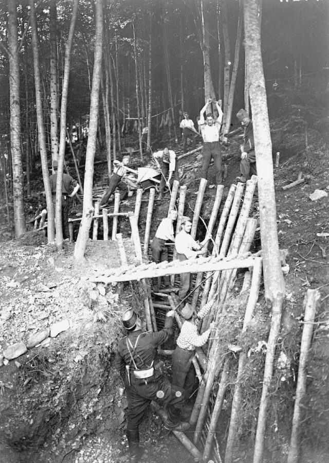 Massive Holzpfähle werden als Stütze in den Schützengraben gehauen