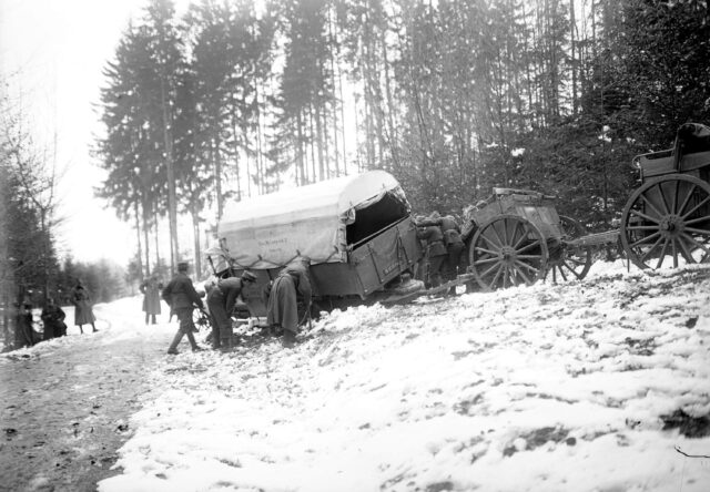 Ein Berna Lastwagen ist als Zugmaschine einer 15cm Haubitze im Morast eingesunken