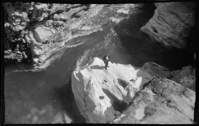 Josef Tcherv debout, en contrebas, sur un rocher surplombant une rivière