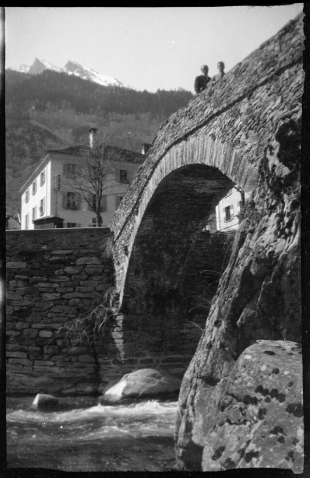 William Ritter et Josef Tcherv traversant un pont en pierre dans un village de montagne