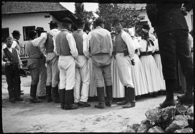 Hommes et femmes de dos, en costumes traditionnels slovaques, sur la place d'un village