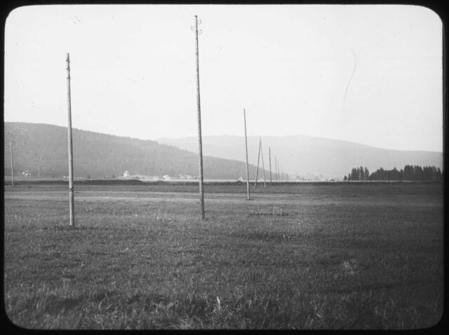 Vue extérieure d'un champ du Val-de-Ruz avec poteaux téléphoniques