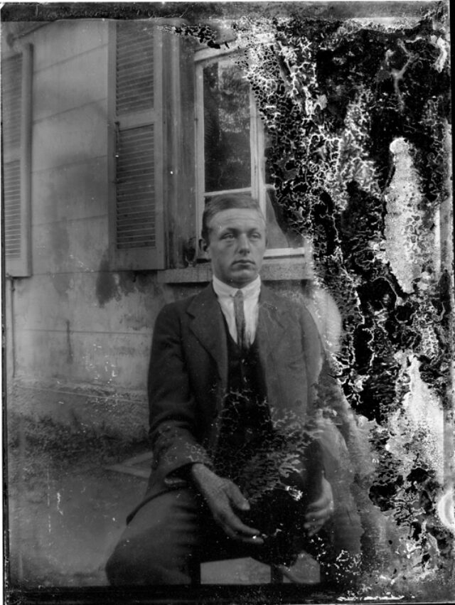 Uomo seduto con cane davanti ad una casa