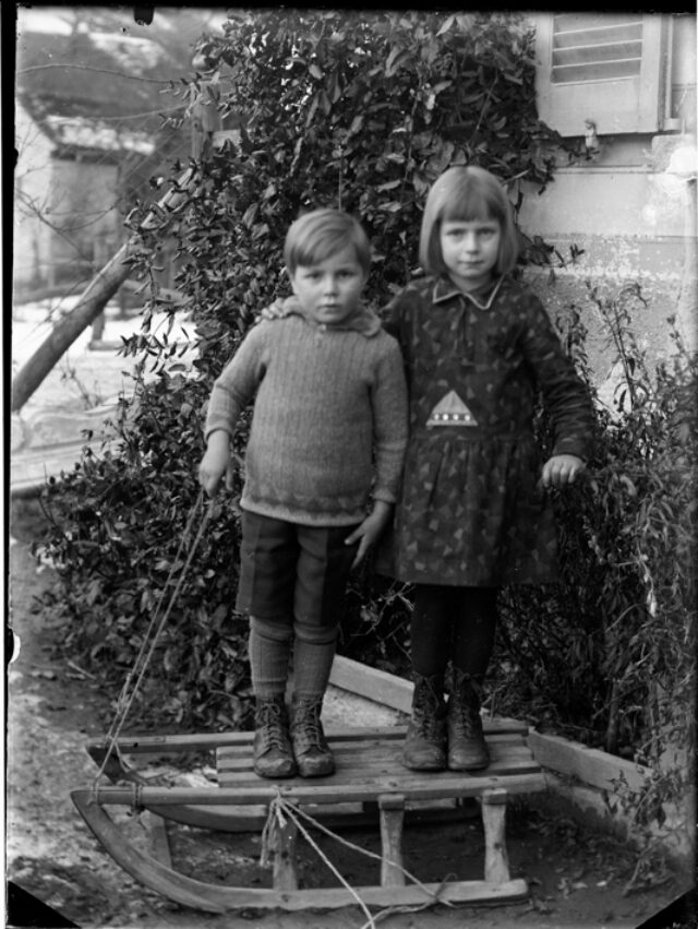 Ritratto di una coppia di bambini all'aperto in piedi su una slitta