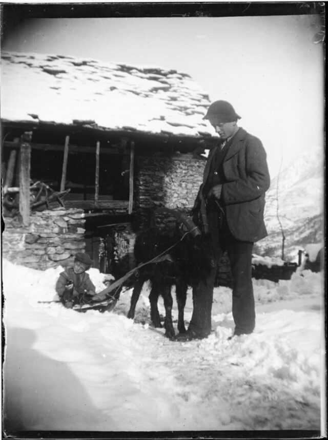 Saul Donetta seduto in una slitta trainata da una capra accanto a un giovane uomo