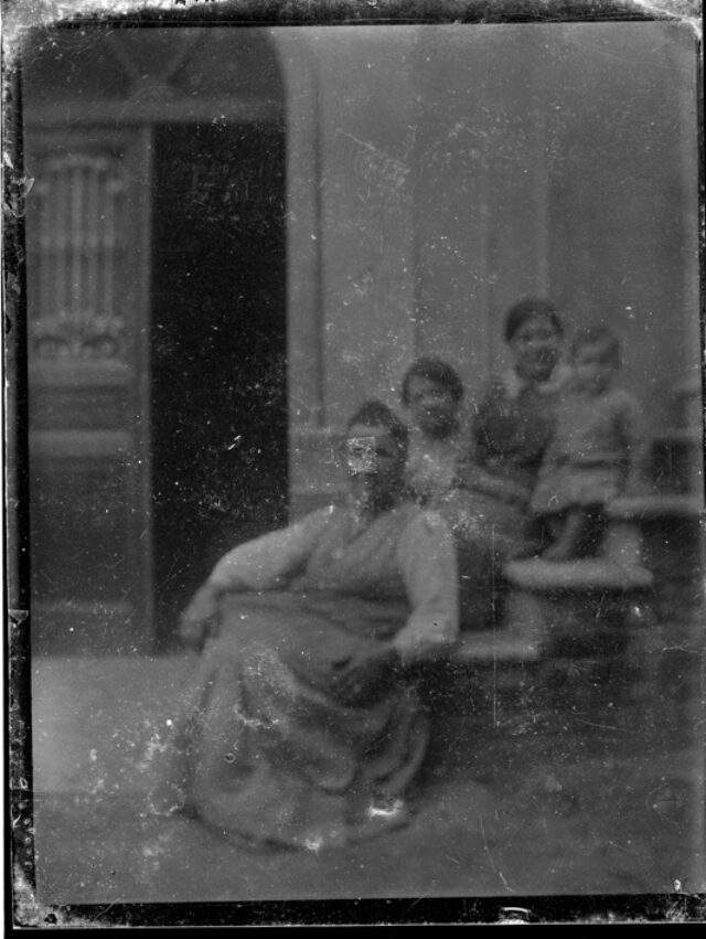 Tre donne e un bambino seduti su una scala davanti a una casa