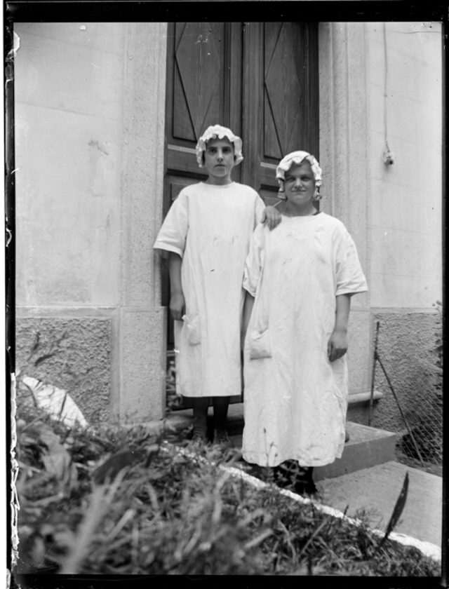 Due operaie della Cima Norma in piedi davanti a un edificio; a destra Gemma Vescovi-Bozzini