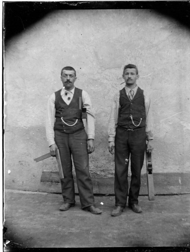 Due uomini con strumenti di lavoro in piedi davanti a un muro