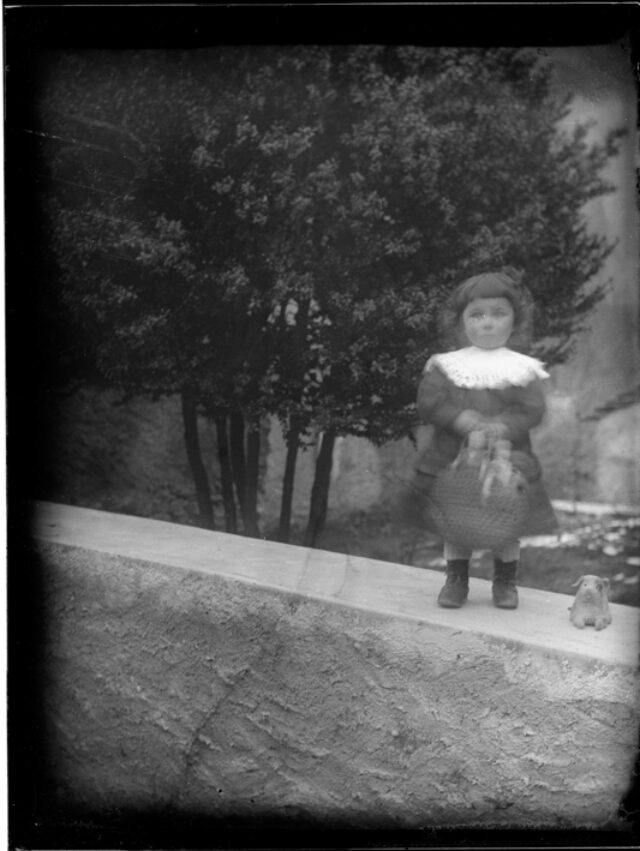 Bambina all'esterno in piedi su un muretto