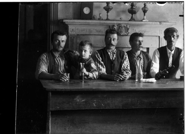 Gruppo di uomini con un bambino seduti a un tavolo in un interno