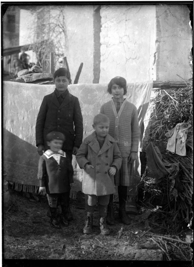 Enrico e Camilla Frusetta con Marcello Jacomelli e un altro bambino, in piedi davanti a un telo appeso all'aperto