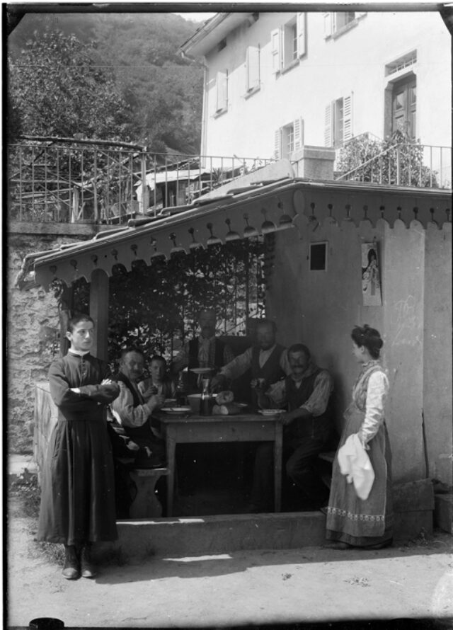 Gruppo di famiglia a tavola in una veranda accanto a una casa