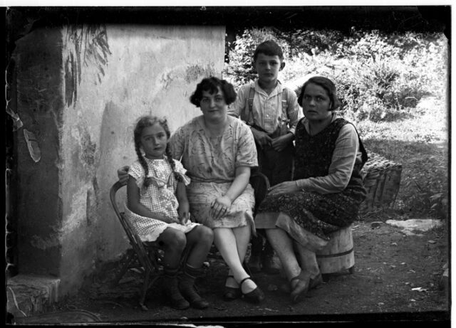Due donne e due bambini seduti in un cortile