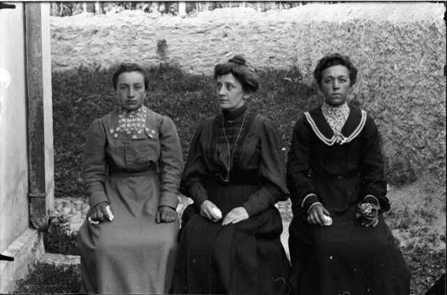 Tre donne sedute davanti a una casa; in mezzo Giulia Bozzini