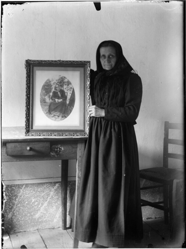 Clotilde Donetta in piedi in un interno con una fotografia della madre Maria