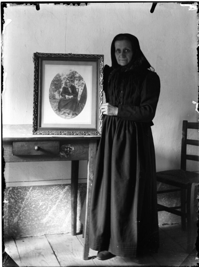 Clotilde Donetta in piedi in un interno con una fotografia della madre Maria