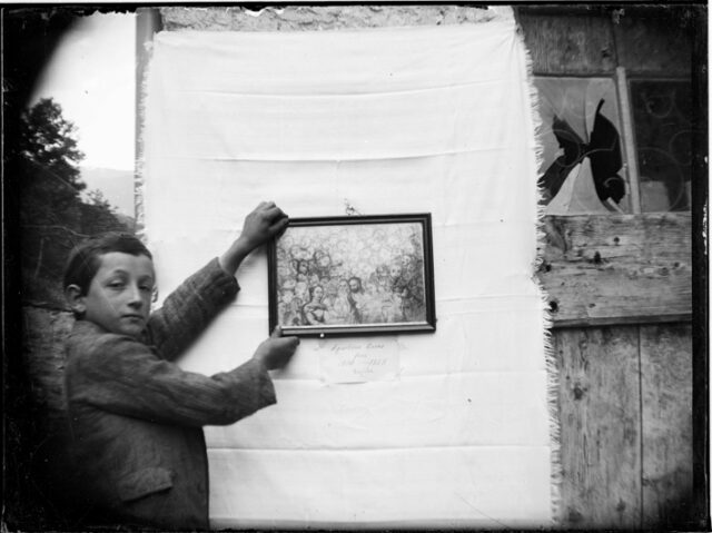 Mario Toschini sostiene un quadro appeso su un tessuto