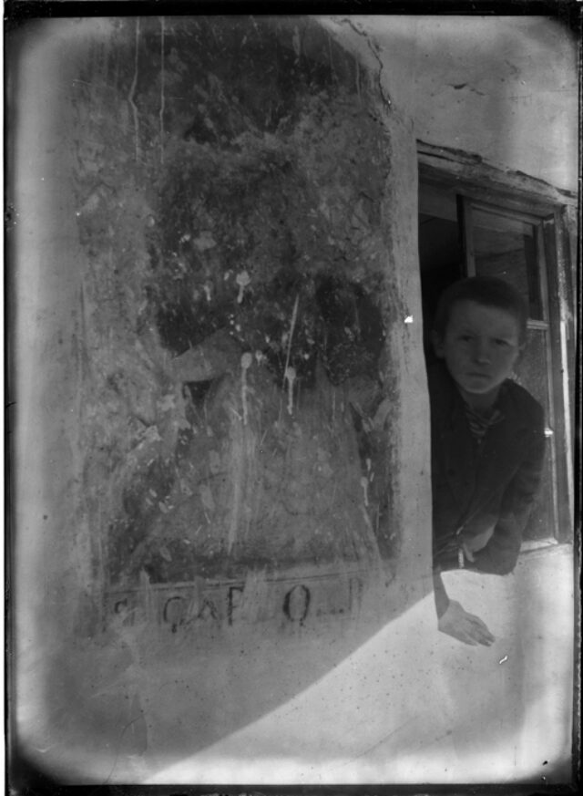 Bambino affacciato a una finestra accanto a un affresco esterno