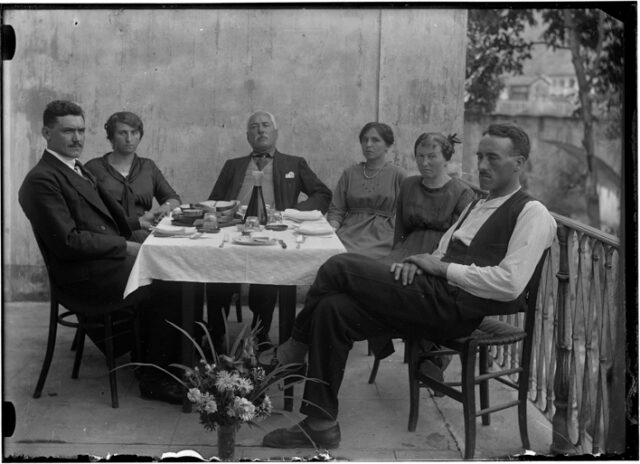 Donne e uomini attorno ad una tavola imbandita