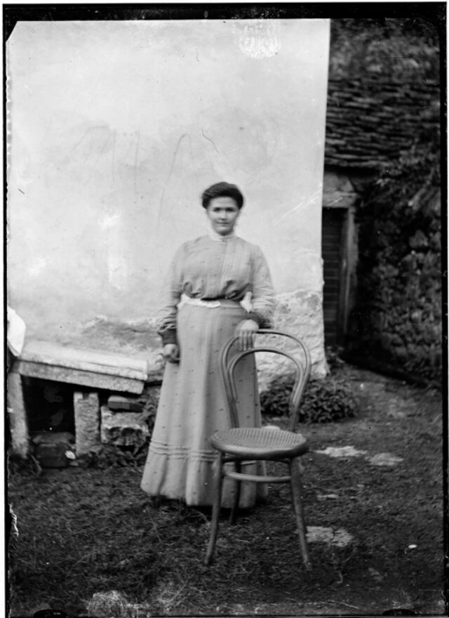 Donna in piedi appoggiata ad una sedia