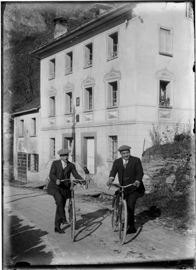 Ritratto di due uonimi con le biciclette davanti ad una casa