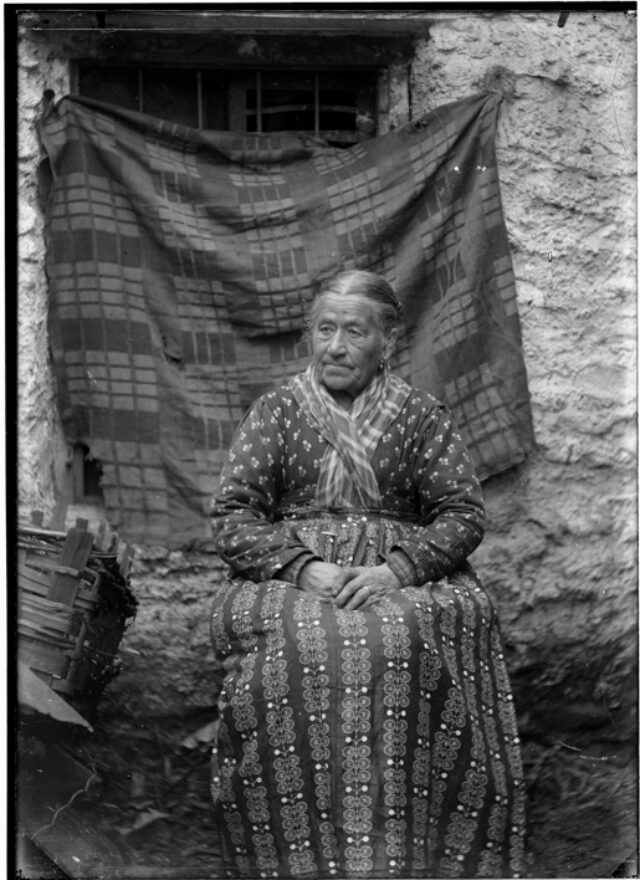 Ritratto di una donna anziana seduta davanti ad un fondale