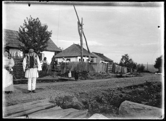 Villageois devant un groupe de maisons et le puits