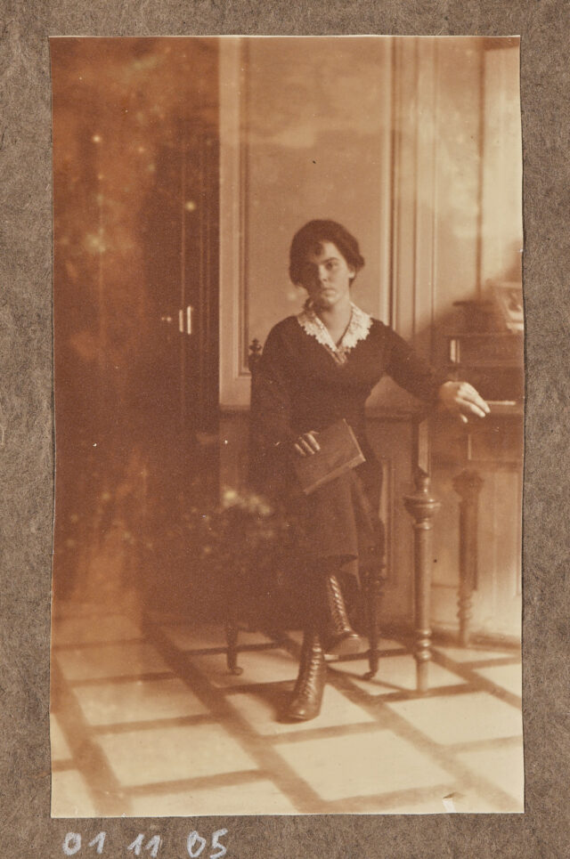Junge Frau (Alice Keller?) mit Buch an Tisch