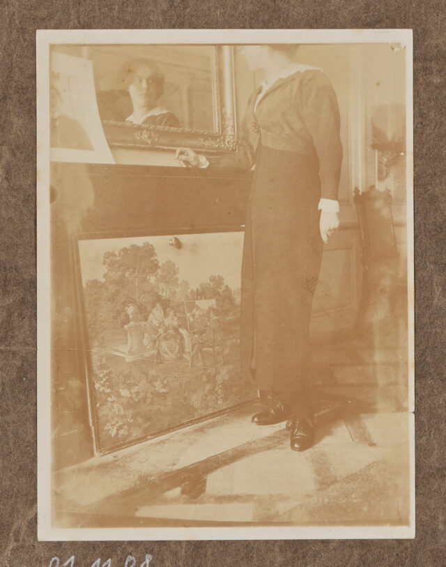 Junge Frau (Alice Keller?) vor einem Bild, schaut sich im Spiegel an.