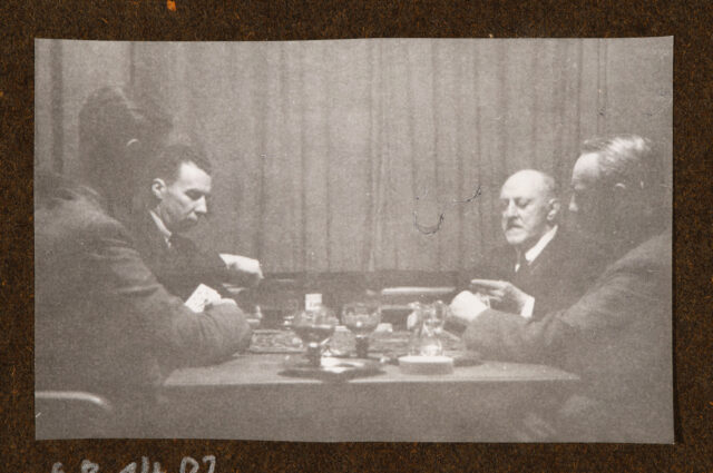 Vier Männer, kartenspielend an einem Tisch