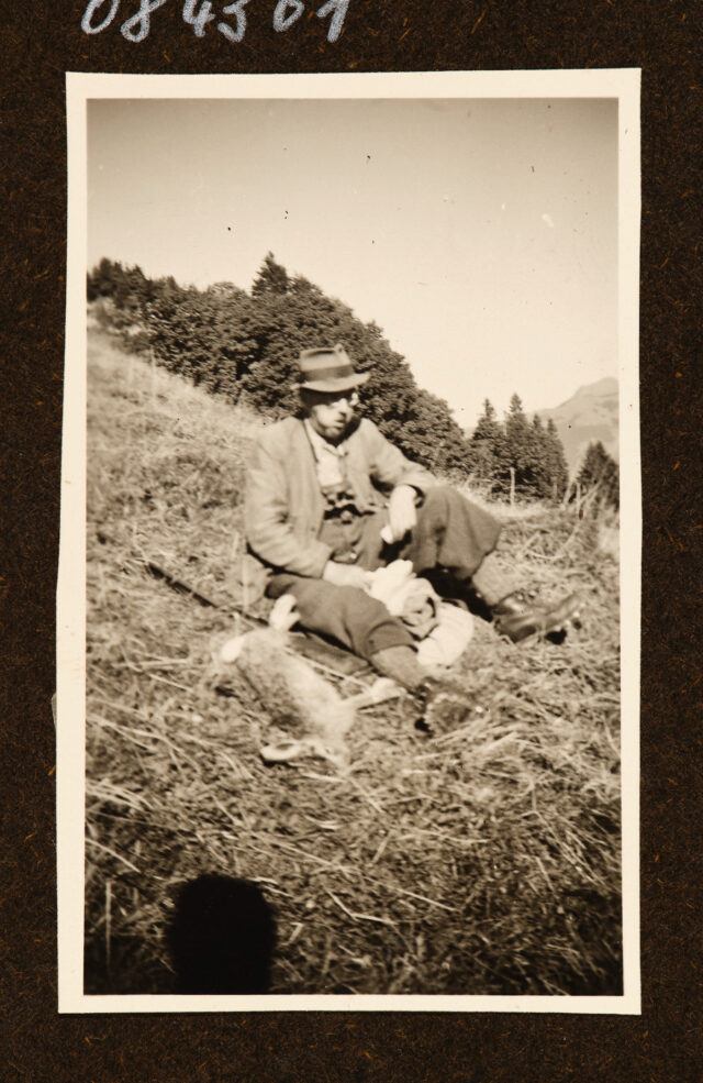 Meinrad Inglin mit erlegtem Hasen in Wiese sitzend