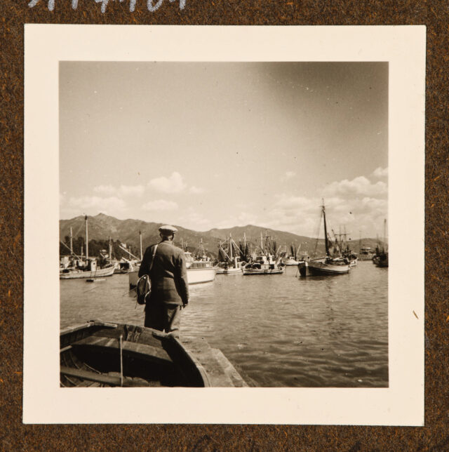 Meinrad Inglin (?, Rückenansicht) vor Bucht mit Fischerbooten