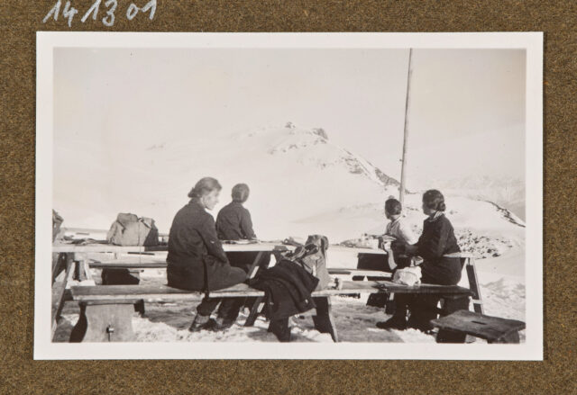 Vier Frauen auf Bänken in verschneiter Berglandschaft