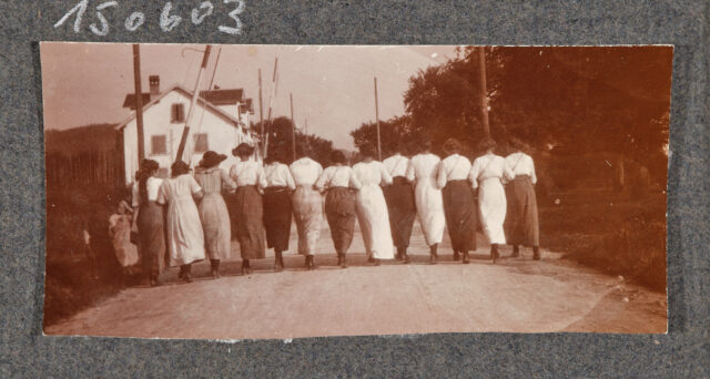 Dreizehn Frauen Arm in Arm von hinten auf Strasse