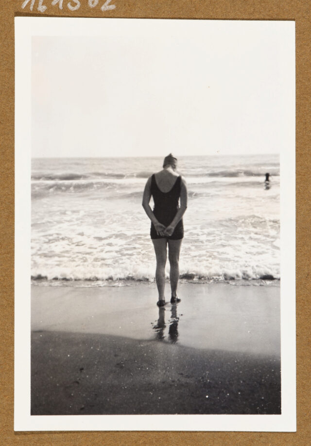 Frau (Rückenansicht) in Badeanzug an Strand