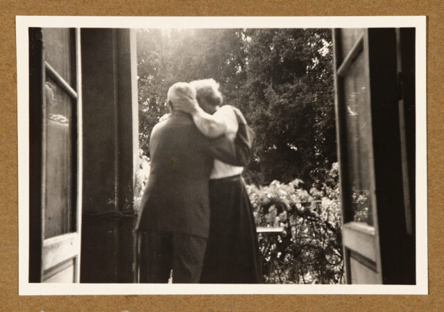 Meinrad Inglin und Bettina Zweifel (beide Rückenansicht) sich umarmend in Balkontür