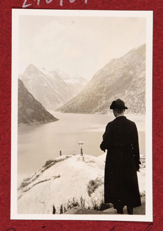 Frau mit schwarzem Hut vor Bergsee