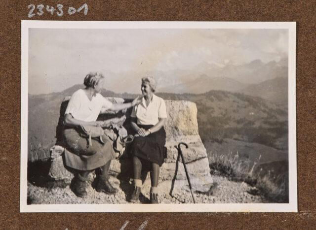 Bettina Zweifel (l.) und andere Frau auf Steinbank vor Bergpanorama