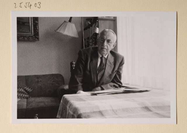 Meinrad Inglin mit Buch an Tisch sitzend