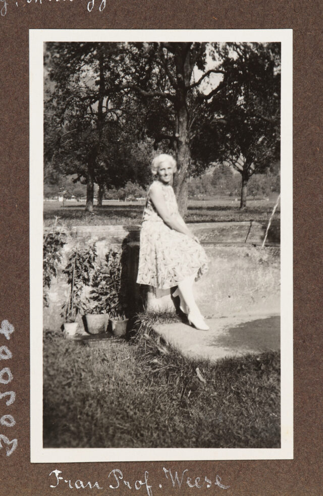 Frau auf Gartenmauer sitzend