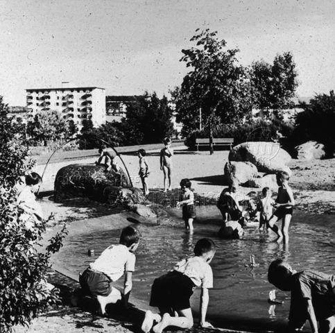 "Freizeitanlagen, Gemeinschaftszentren: Planschbecken Bachwiesen, Zürich" - Kinder spielen in einem künstlichen Becken auf dem Spielplatz; um 1970