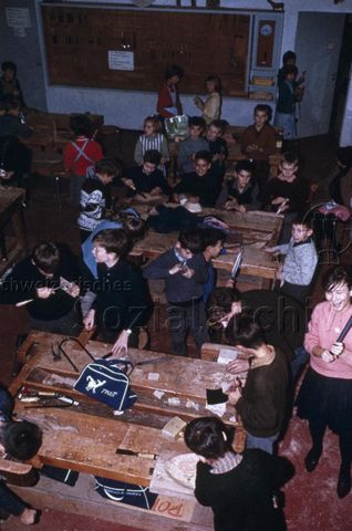 "Freizeitanlagen, Gemeinschaftszentren: Werkstatt Bachwiesen, Zürich" - Kinder, um Werkbänke sitzend, verrichten unterschiedliche Holzarbeiten; um 1975
